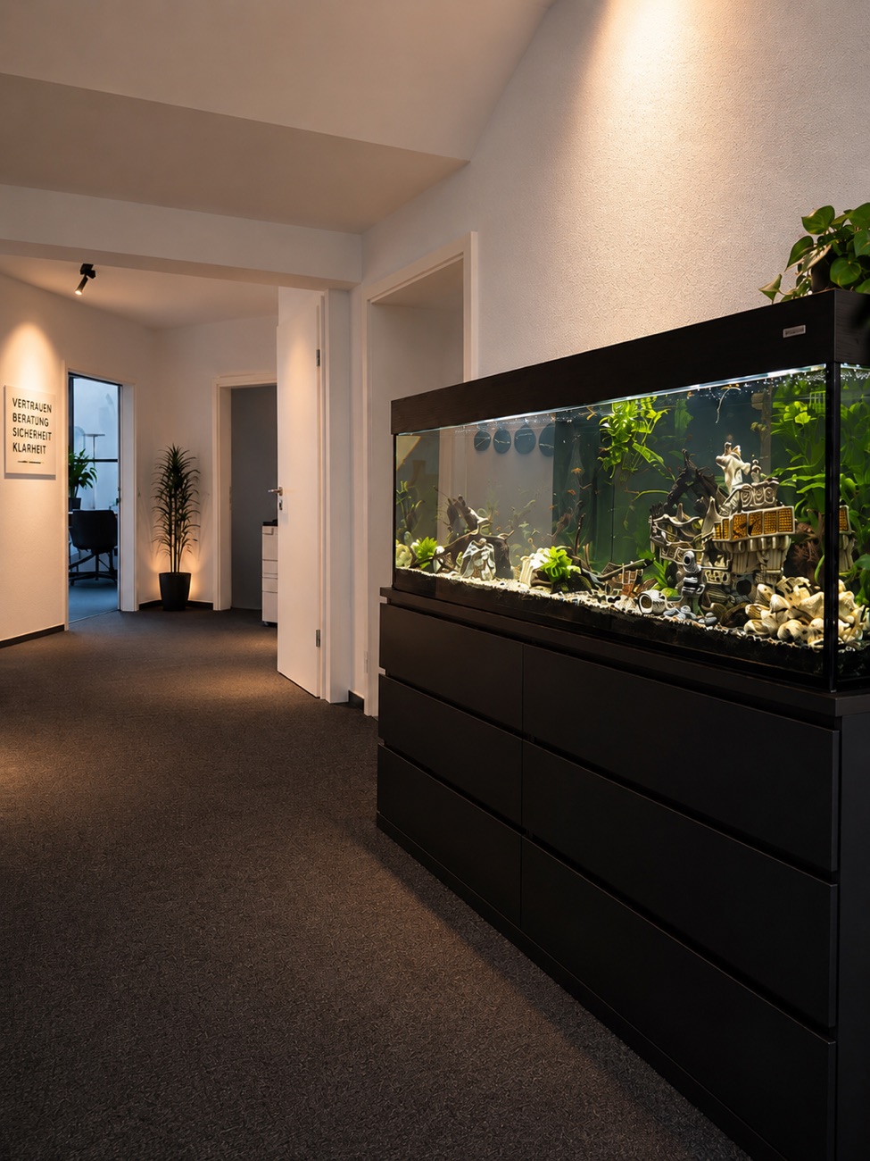 Büroflur der Agentur mit großem Aquarium und dem Leitbild Vertrauen, Beratung, Sicherheit, Klarheit